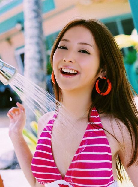 Long haired asian cutie having fun in a striped hot pink bikini